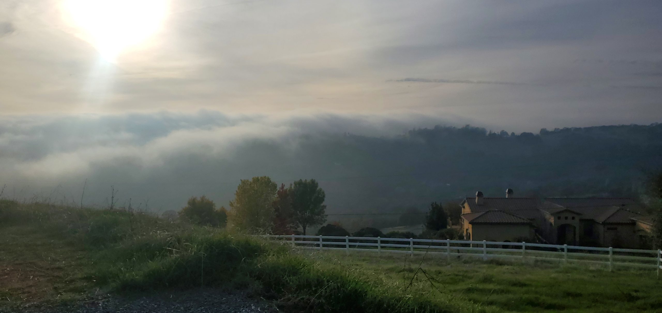 Sun poking out of fog rolling over the hills
