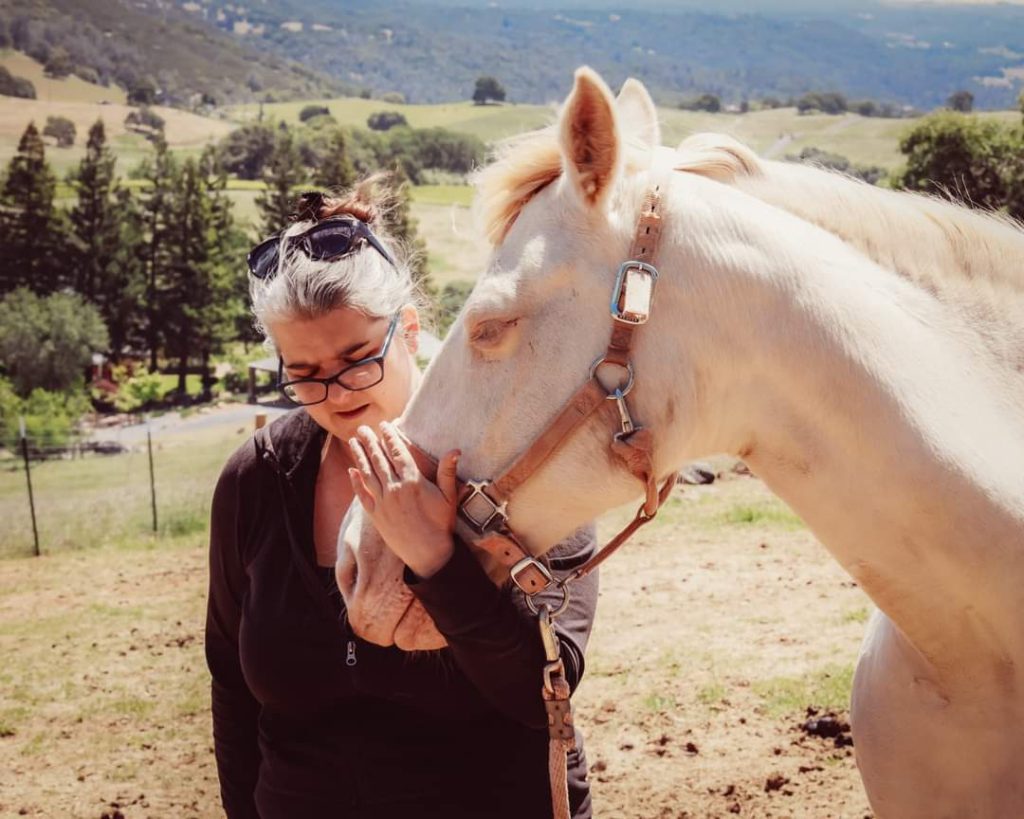 Jalaina gently embracing a horse in the pasture