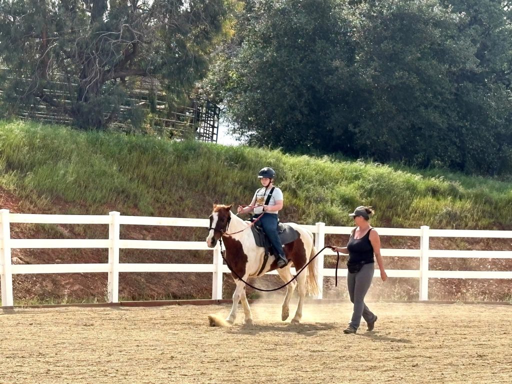 Jalaina leading a horse and rider in the arena